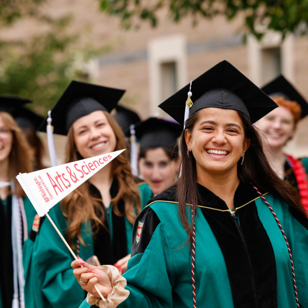 Washington University in St. Louis graduates holding Arts & Sciences flags.