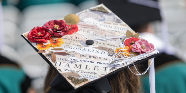 Artistic cap of a graduating Washington University in St. Louis student adorned with vibrant flowers and fragments from renowned literary works, showcasing creativity and passion for literature.