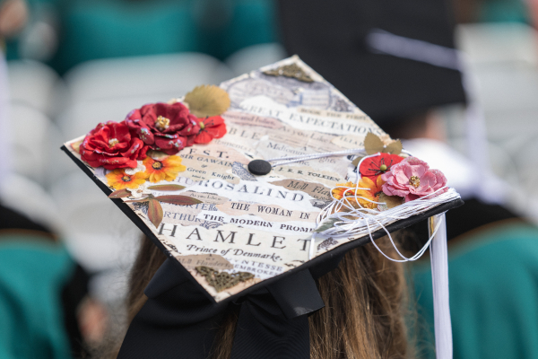 Artistic cap of a graduating Washington University in St. Louis student adorned with vibrant flowers and fragments from renowned literary works, showcasing creativity and passion for literature.