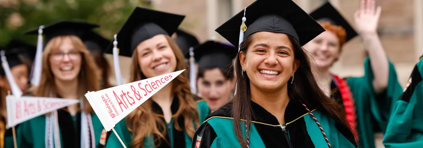 Washington University in St. Louis graduates holding Arts & Sciences flags.
