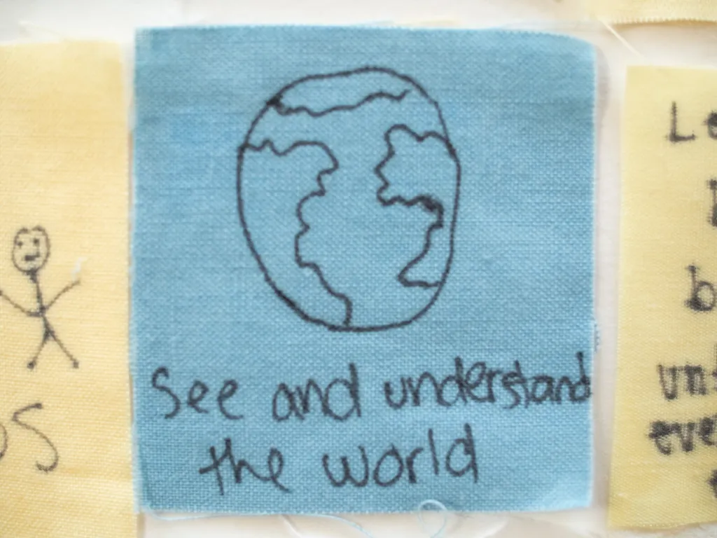 Close up of a senior quilt square that reads, "see and understand the world."