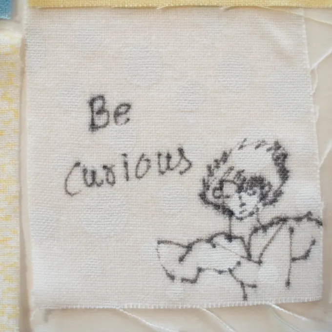 Close up of a senior quilt square that reads, "be curious."