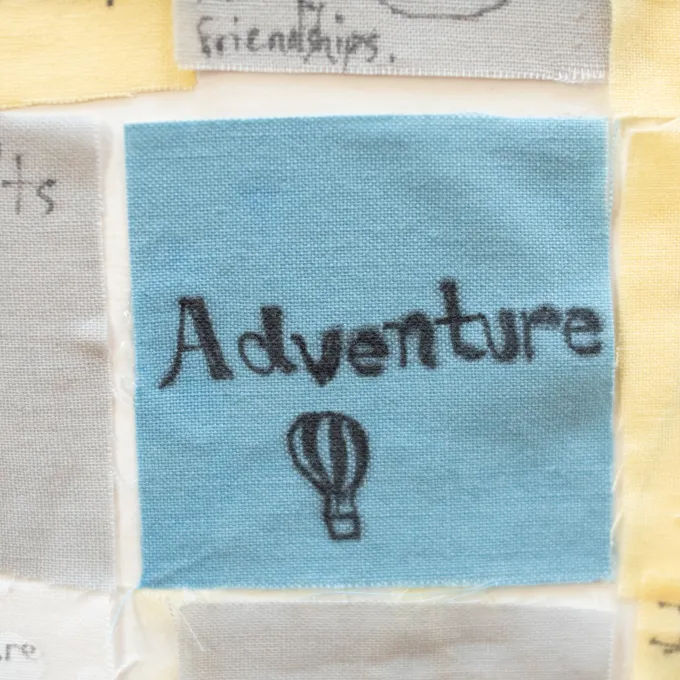Close up of a senior quilt square that reads, "Adventure."
